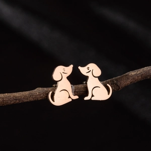 Cute puppy shaped rose gold stainless steel stud earrings displayed on a rustic branch