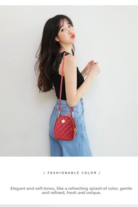 Détail du sac matelassé rouge avec emblème trèfle doré et surpiqûres de précision