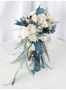 Close-up of cascading bridal bouquet with white roses, blue berries and eucalyptus