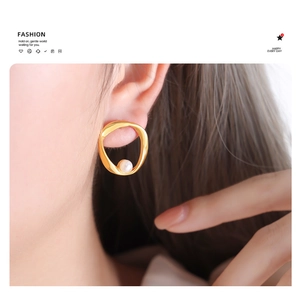Detailed view of irregular gold ring earrings with elegant round white pearl charm
