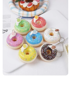 Détail de 7 porte-clés donuts colorés avec pépites et crème sur un plateau blanc