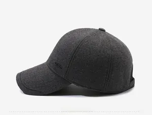 Side view of dark gray woolen baseball cap with a metal logo emblem and warm texture