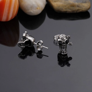 Macro shot of vintage silver skull earrings with black crystal eyes on dark stone