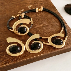 Detail of vintage gold jewelry set with spiral patterns and black oval gemstones