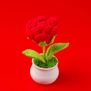 Detailed view of a hand-knitted red rose in a small white pot with a vibrant red background