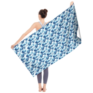Detail of a large microfiber beach towel featuring a blue and white ocean wave print