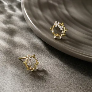 Detailed macro shot of gold flower wreath earrings with micro-set white cubic zirconia stones
