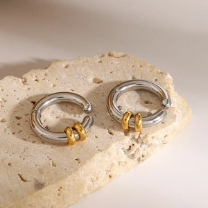 Two-tone silver and gold stainless steel hoop earrings on natural stone background