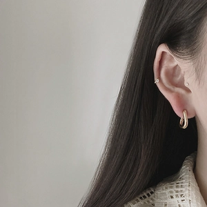 Minimalist gold U-shaped hoop earrings and ear cuff set worn by a female model
