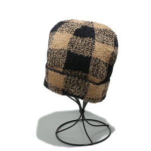 Close-up of checkerboard knit beanie texture on a minimalist black metal hat stand
