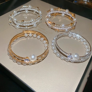 Detail of multi-layer spiral bracelets with pearls and sparkling zircons in a gift box