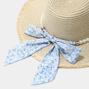 Straw sun hat with pearl trim and blue floral bow featuring a wide frayed brim