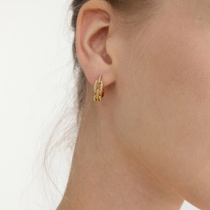 Gros plan de boucles d'oreilles maillons dorés avec zircons blancs sur une femme