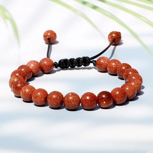 Macro view of red brown goldstone beaded bracelet with adjustable black braided cord