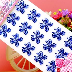 Detailed view of blue flower-shaped acrylic rhinestone stickers on a pink background