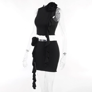 Detail of black two-piece set featuring 3D floral accents and ruffled miniskirt