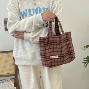Detail of vintage plaid tote bag with textile texture and brand label in casual setting