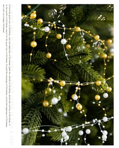Detailed view of white and gold bead garland wrapped on a green Christmas tree branch