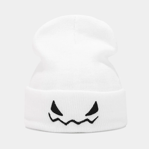 Détail du bonnet en tricot blanc avec broderie de diable noir et texture côtelée