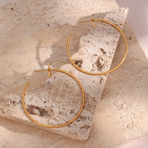 Detailed view of a gold-plated oversized hoop earring with a star charm on stone