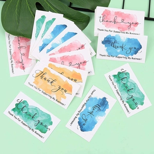 Watercolor thank you business card set with ink wash designs on a light green desk