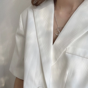 Detail of 925 silver crescent moon pendant with crystals on a white blazer model