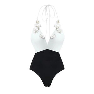 Detail of elegant black and white bikini with 3D floral accent on halter neckline