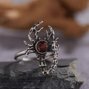 Detailed macro shot of a silver scorpion ring with a round red garnet stone in punk style