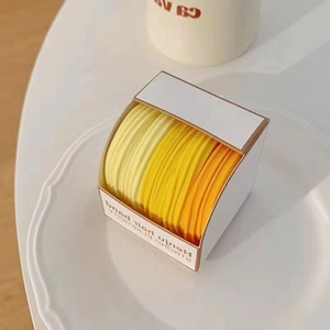 Detail of high-elastic gradient hair ties in yellow and orange colors in a white box