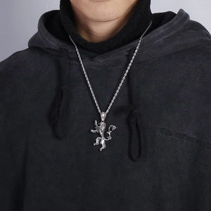Detailed view of silver lion pendant on twisted steel chain worn by a male model