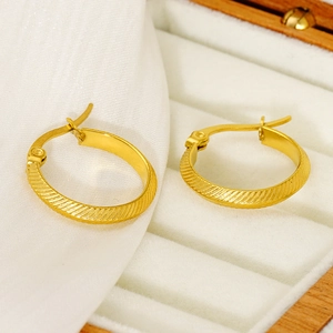 Minimalist gold-plated twist hoop earrings with spiral texture on a white velvet cushion