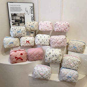 Quilted floral and heart pattern cotton makeup bags displayed on white pedestals