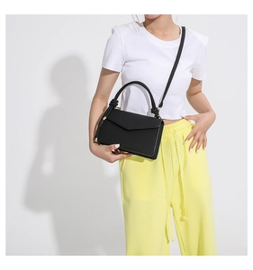 Close-up of black vertical stripe crossbody bag with woven handle on white T-shirt