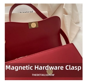 Detail of the golden magnetic buckle and fine stitching on the red leather shoulder bag