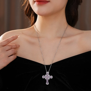 Close-up of zircon cross pendant necklace on neck with purple gems and silver chain