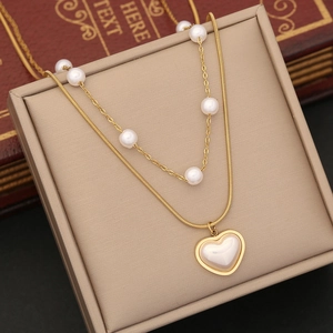Multi-layer gold necklace with pearls and heart pendant displayed on jewelry box