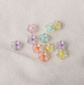 Macro detail of colorful transparent acrylic flower beads on linen fabric for DIY jewelry