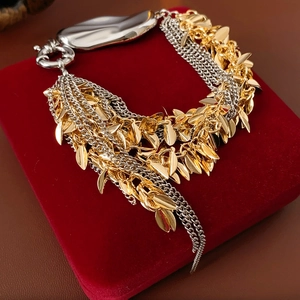 Detail of layered gold leaf charms and silver chains on red velvet jewelry box