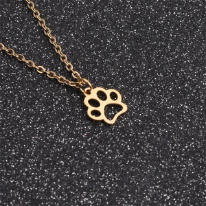 Macro shot of polished gold dog paw pendant with delicate chain on black background