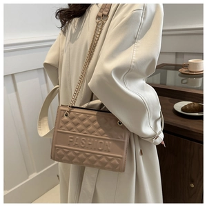 Detail of beige quilted handbag featuring gold chain strap and embossed fashion logo