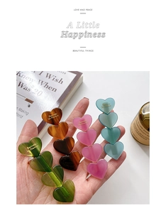 Detailed view of four colorful acetate heart-shaped hair clips with gold lettering