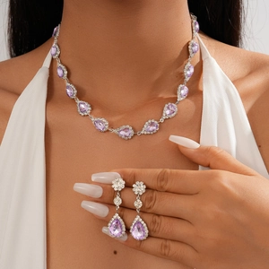 Elegant silver necklace and teardrop purple crystal earrings set on a female model
