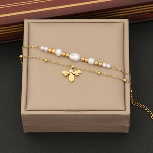 Vue détaillée du bracelet double couche avec perles blanches et pendentif abeille doré