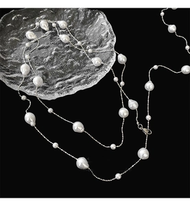 Detailed view of long baroque pearl sweater chain with irregular pearls on a black background