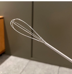 Macro view of stainless steel whisk wires and spiral handle detail for home baking