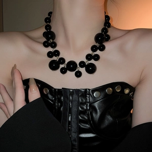 Detailed close-up of chunky black irregular beads and gold clasp on a fashion necklace