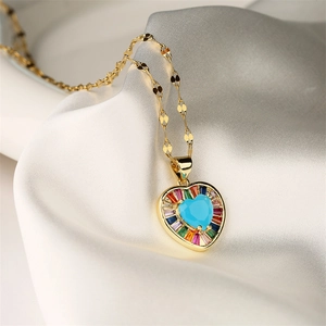 Macro shot of gold heart necklace with turquoise stone and colorful gemstones on white silk