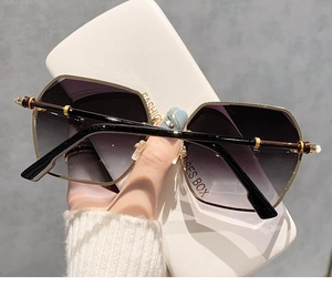 Nahaufnahme der randlosen Sonnenbrille mit lila Farbverlauf und goldenen Metallbügeln