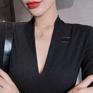 Detailed view of micro-paved gourd pendant necklace on a black V-neck sweater