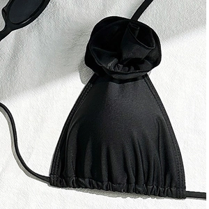 Detail of black bikini top featuring elegant 3D rose applique and satin finish texture